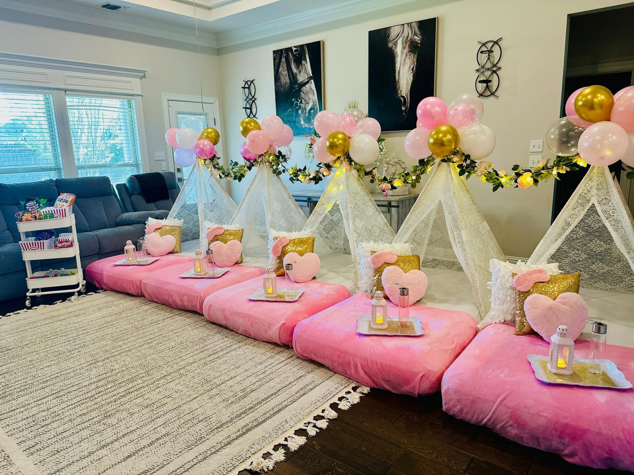 A styled Pitched Fort sleepover with pink and gold tents, balloons, and cozy details